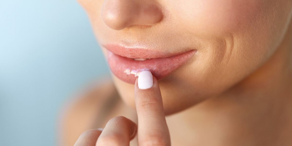 Close-up shot of a woman touching her healthy, fuller lips - providing care and protection for healthier lips.