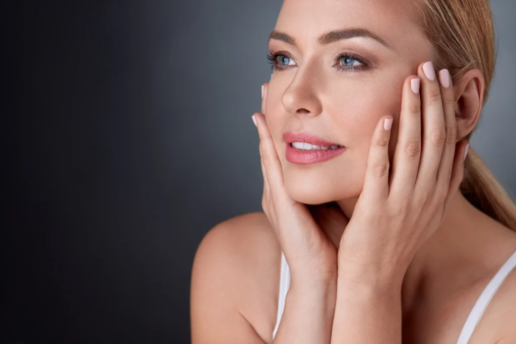 A woman touching her rejuvenated face with a radiant and youthful complexion after undergoing Volume Rejuvenation.