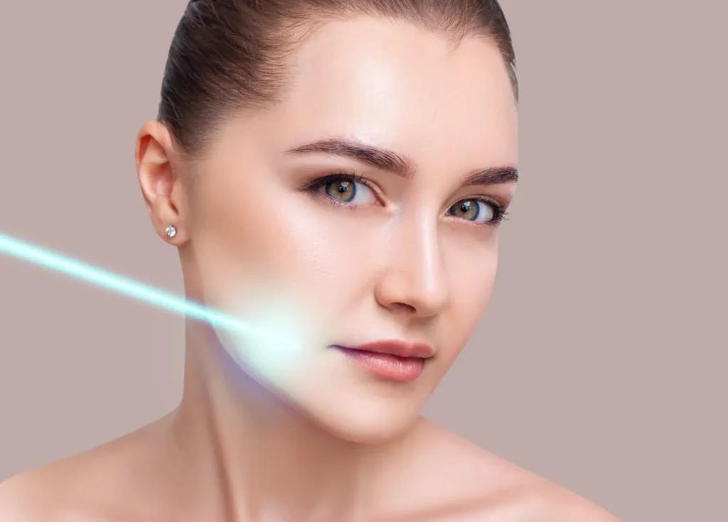 Woman facing the camera with a blue laser-like light directed across her lower cheek.